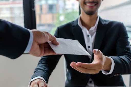 Man handing envelope to another man making personal superannuation contributions